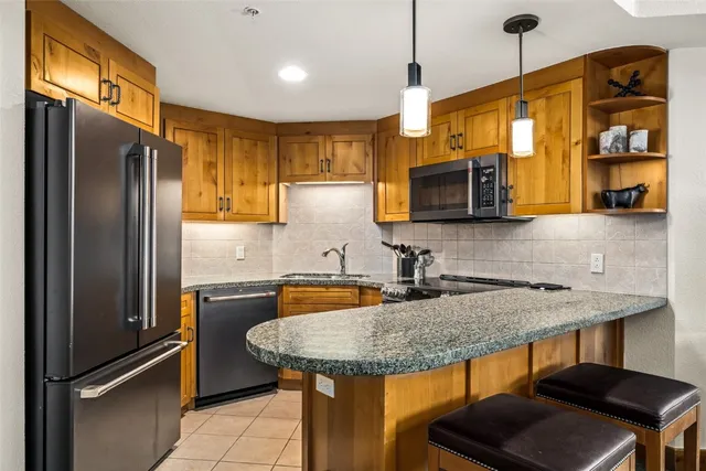 a kitchen with stainless steel appliances granite countertop a sink a microwave refrigerator and chairs