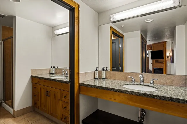 a bathroom with a granite countertop double vanity sink and a mirror