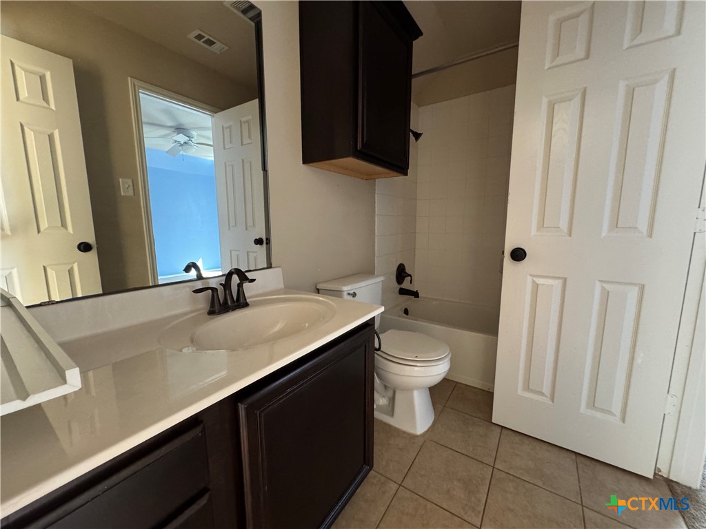6801 Modesto Road Killeen, TX 76542 - Photo 22 of 26 a bathroom with a granite countertop sink a large mirror and a toilet