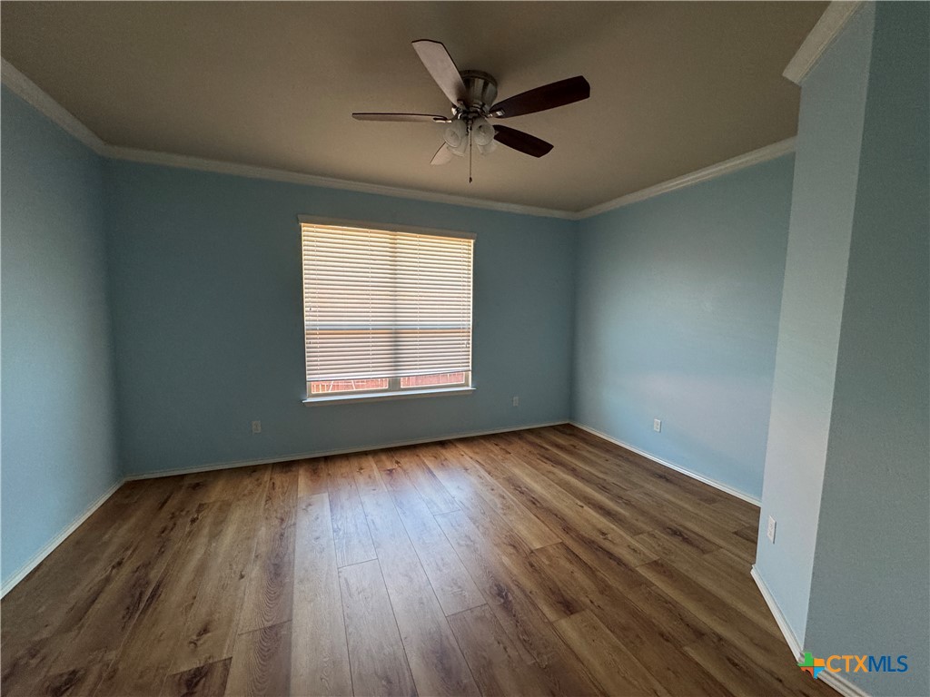 6801 Modesto Road Killeen, TX 76542 - Photo 23 of 26 an empty room with wooden floor chandelier fan and windows