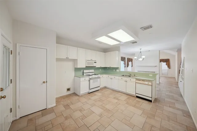 a large kitchen with white cabinets and stainless steel appliances