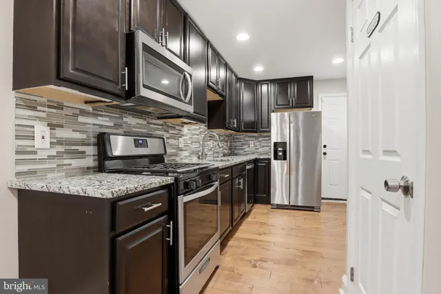 a kitchen with stainless steel appliances granite countertop a refrigerator a sink and wooden cabinets