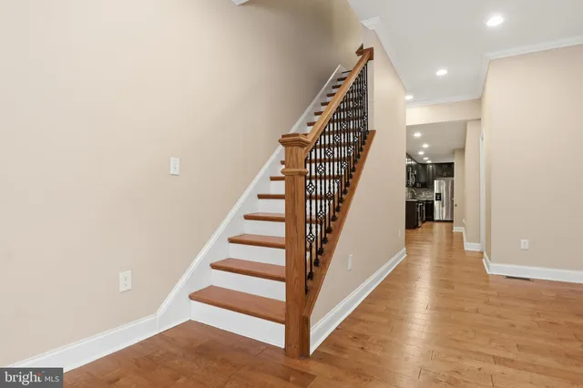 a view of an empty room with wooden floor and stairs