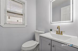 634 Newhall Street Hamden, CT 06517 - Photo 12 of 28 a bathroom with a toilet a sink a mirror and a window