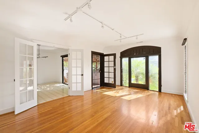 a view of an empty room with wooden floor and a window