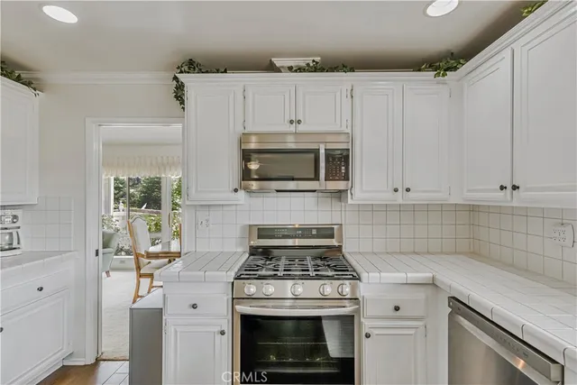 a kitchen with white cabinets and stainless steel appliances