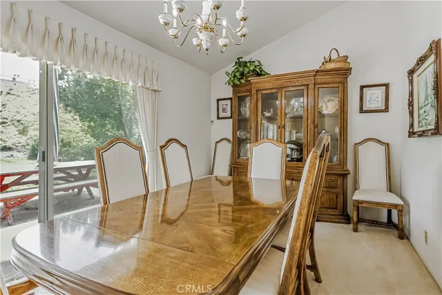 a view of a dining room with furniture a chandelier and large windows