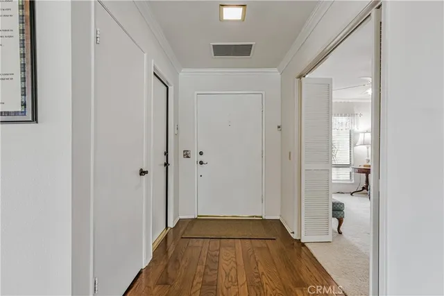 a view of a hallway with wooden floor and a bathroom