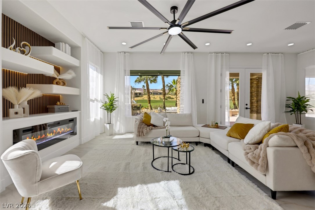 5015 Rivedro Street Las Vegas, NV 89135 - Photo 5 of 91 A spacious living room offering a fireplace and outdoor views of the golf course and palm trees.