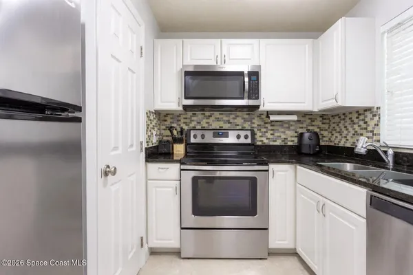 a kitchen with granite countertop white cabinets and stainless steel appliances