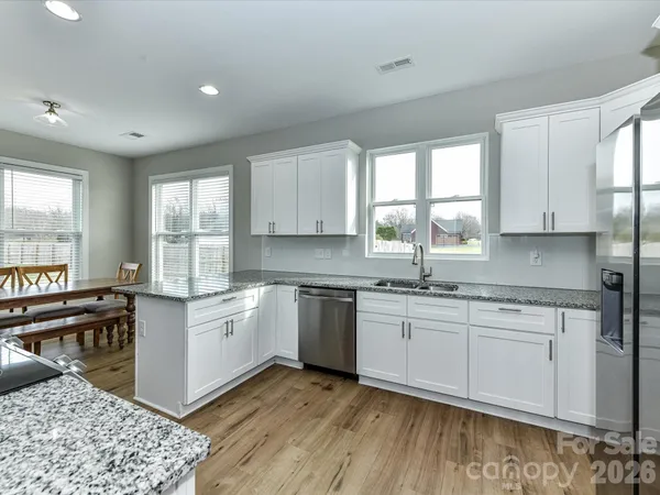 a kitchen with stainless steel appliances granite countertop a stove a sink dishwasher and a microwave oven with white cabinets