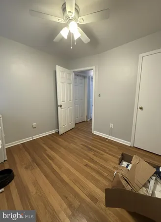 an empty room with wooden floor and fan
