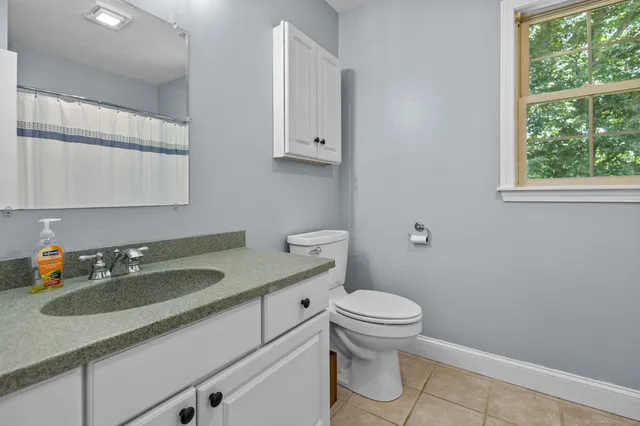 a bathroom with a granite countertop sink a toilet and a window