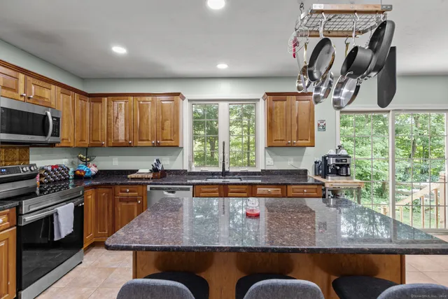 a kitchen with kitchen island granite countertop a stove top oven a sink a counter space and cabinets
