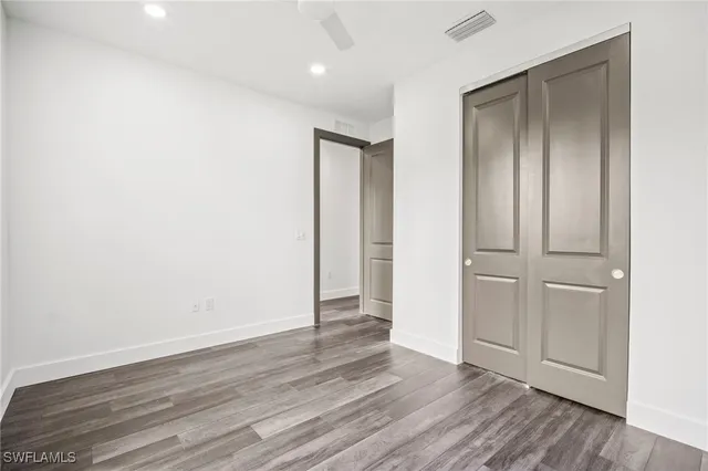 an empty room with wooden floor & closet area