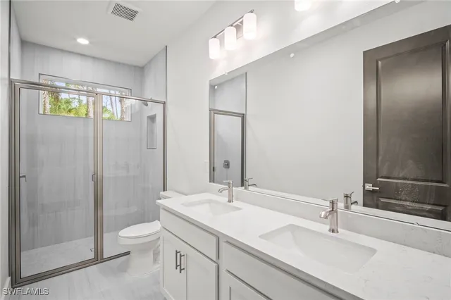 a bathroom with a double vanity sink toilet and shower