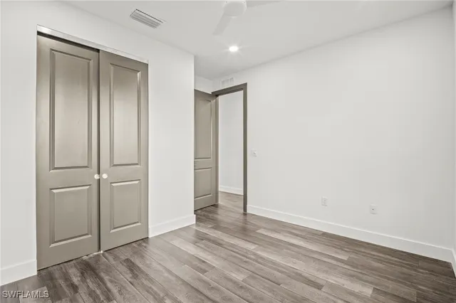 an empty room with wooden floor and closet area