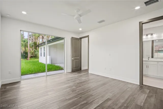 a view of an empty room with wooden floor and fan