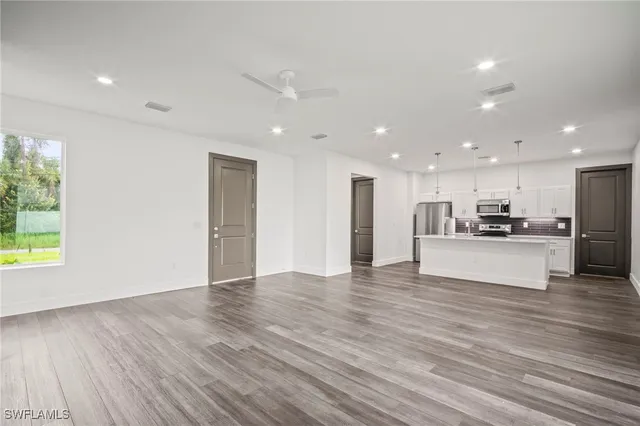 a view of kitchen with kitchen island wooden floor granite counter tops and white cabinets