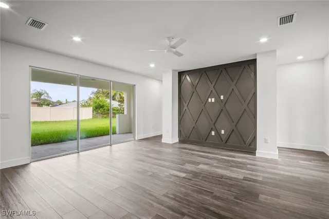 a view of an empty room with wooden floor and a gate