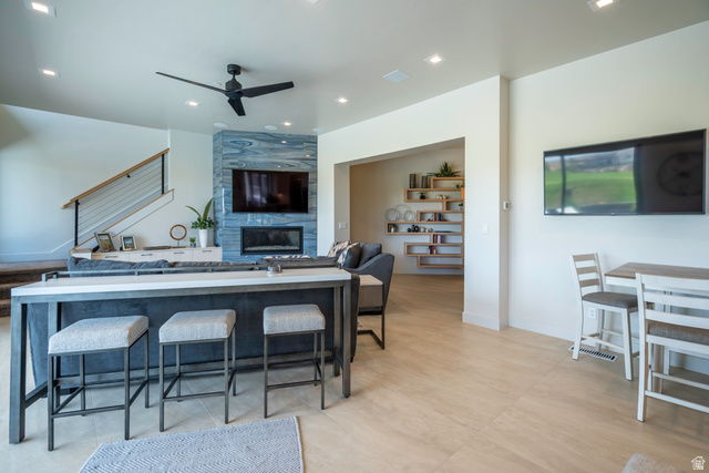 3606 South Cypress Road Hurricane, UT 84737 - Photo 69 of 69 Kitchen featuring a tile fireplace, a ceiling fan, open floor plan, recessed lighting, and a breakfast bar