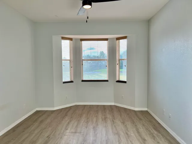 an empty room with wooden floor and windows