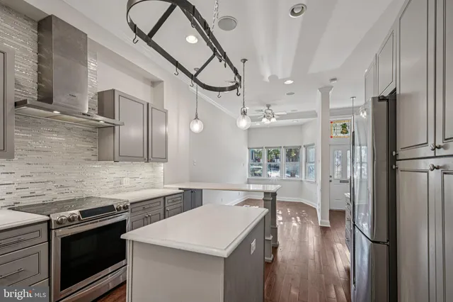 a kitchen with stainless steel appliances granite countertop a refrigerator a stove and a sink with wooden floor