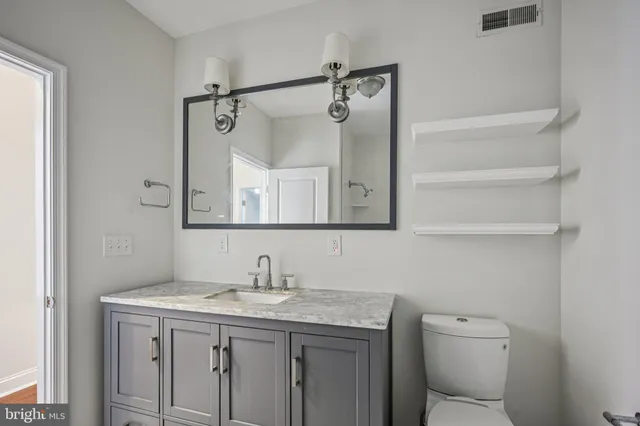 a bathroom with a granite countertop sink a toilet and a mirror