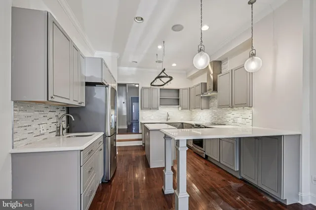 a kitchen with stainless steel appliances granite countertop a sink a stove and a wooden floors