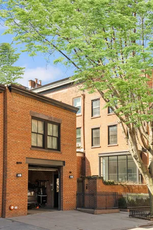 a view of a brick house with a yard and large tree