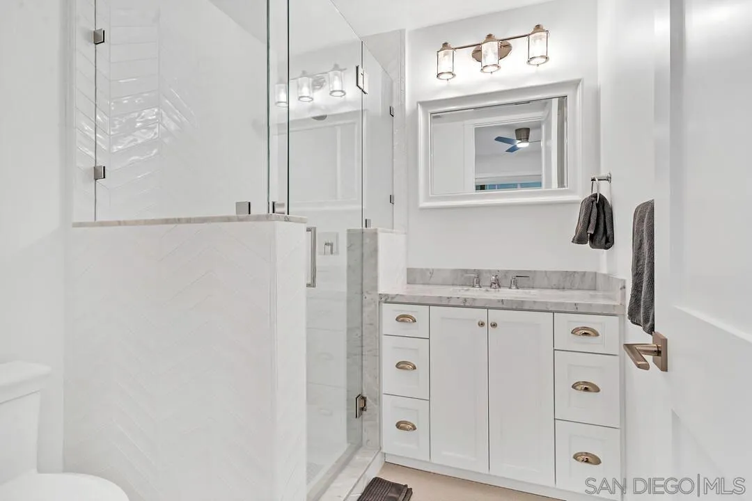 949 D Avenue Coronado, CA 92118 - Photo 23 of 28 a bathroom with a granite countertop sink vanity mirror and shower