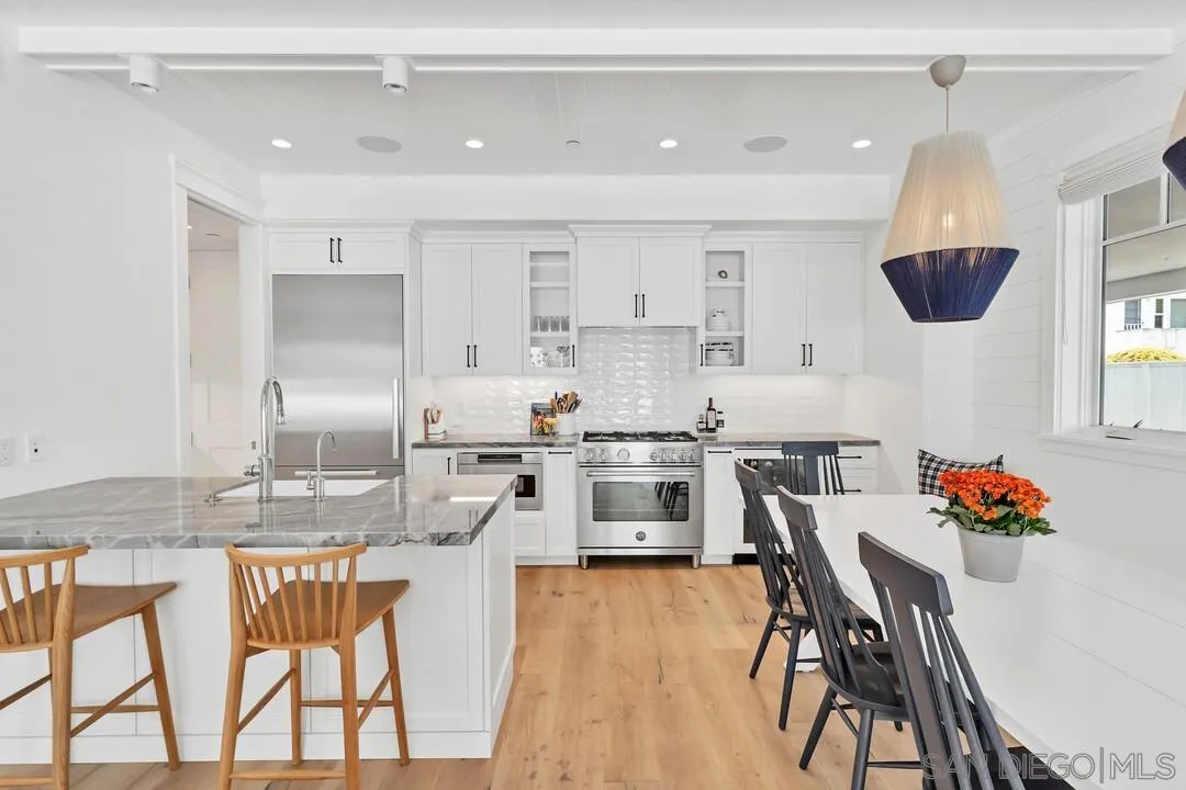 949 D Avenue Coronado, CA 92118 - Photo 5 of 28 a kitchen with stainless steel appliances kitchen island granite countertop a dining table chairs and white cabinets