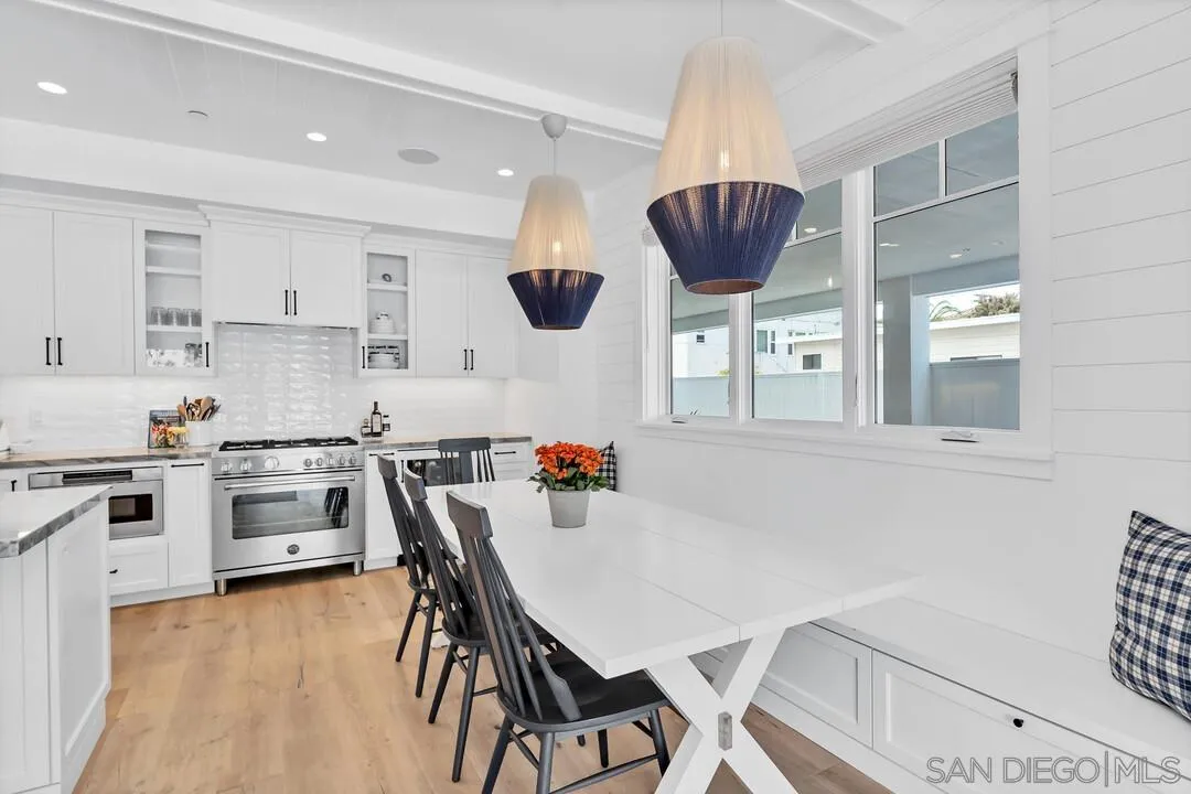 949 D Avenue Coronado, CA 92118 - Photo 8 of 28 a kitchen with stainless steel appliances granite countertop a stove top oven a sink a dining table and chairs with wooden floor