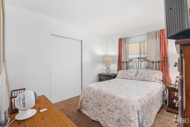 a bedroom with a bed and a flat tv screen on dresser