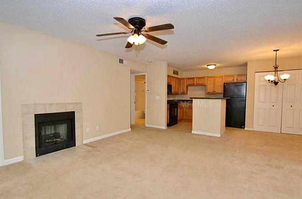390 Woodside Drive, Unit 202 Altamonte Springs, FL 32701 - Photo 8 of 10 a view of a livingroom with a fireplace a ceiling fan and a kitchen