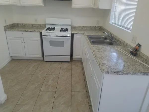 a utility room with granite countertop white cabinets and white appliances