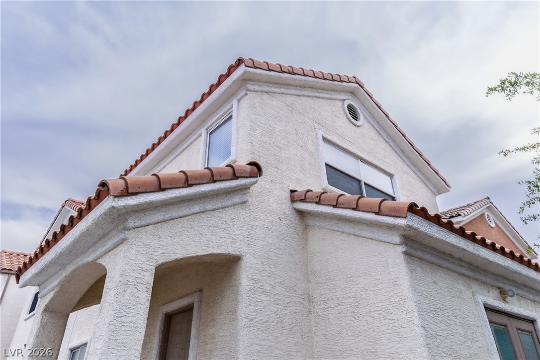 1409 Sycamore Spring Court Las Vegas, NV 89128 - Photo 28 of 28 This building features traditional roof tiles and a textured stucco finish under a wide-open sky.