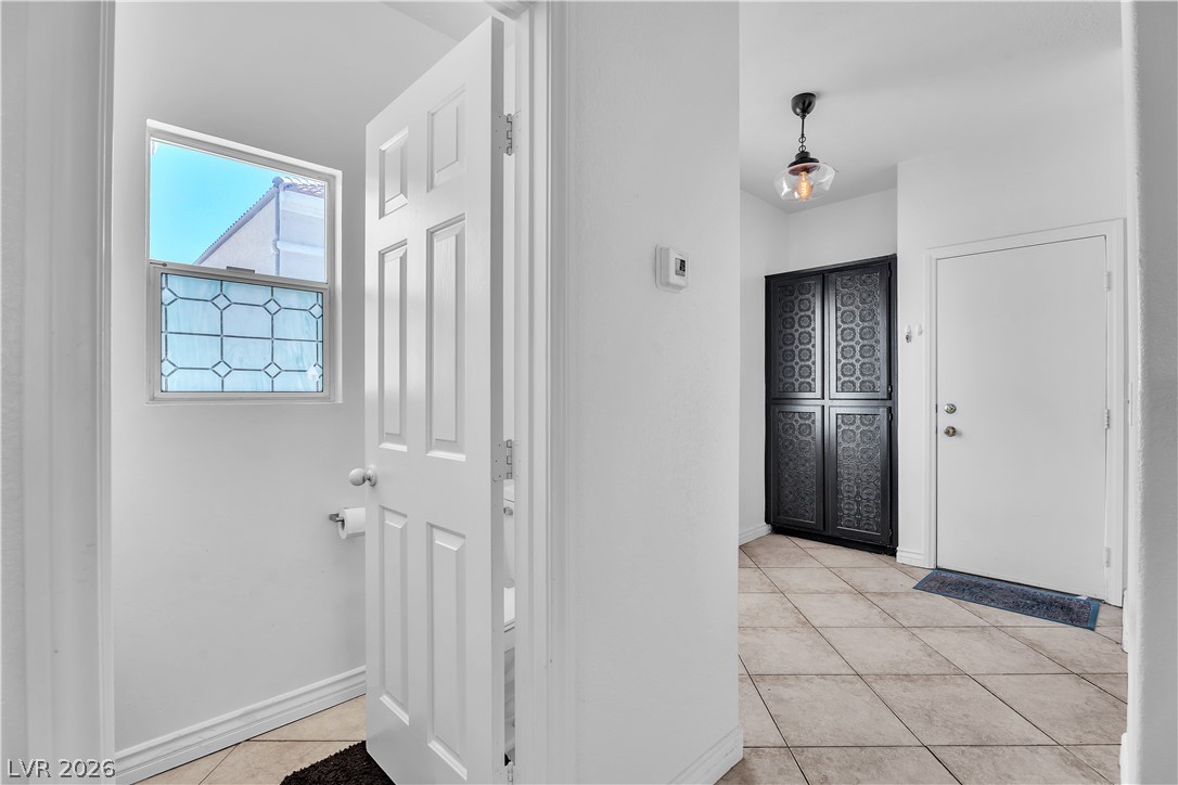 1409 Sycamore Spring Court Las Vegas, NV 89128 - Photo 8 of 28 This inviting entry features durable tile flooring, a window with decorative glass, and a stylish pendant light.