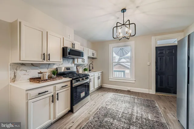 a kitchen with stainless steel appliances granite countertop a stove top oven a sink dishwasher and white cabinets with wooden floor