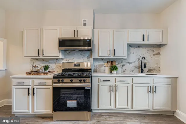 a kitchen with white cabinets and appliances