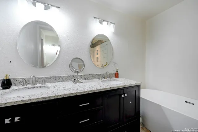 a bathroom with a granite countertop double vanity and a mirror