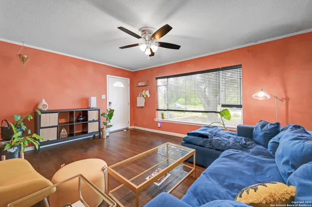a living room with furniture a ceiling fan and a large window