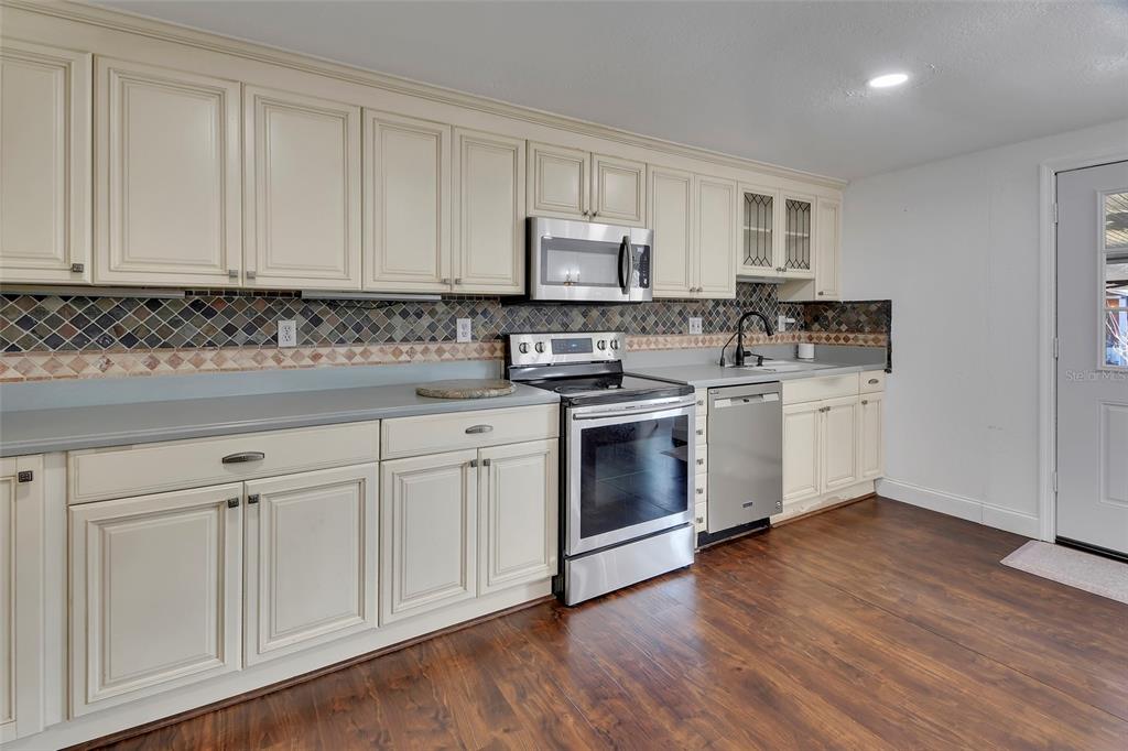 115 Juan Road DeBary, FL 32713 - Photo 13 of 41 a kitchen with cabinets stainless steel appliances a sink and wooden floor