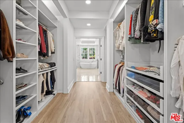 a view of walk in closet with clothes and shoes