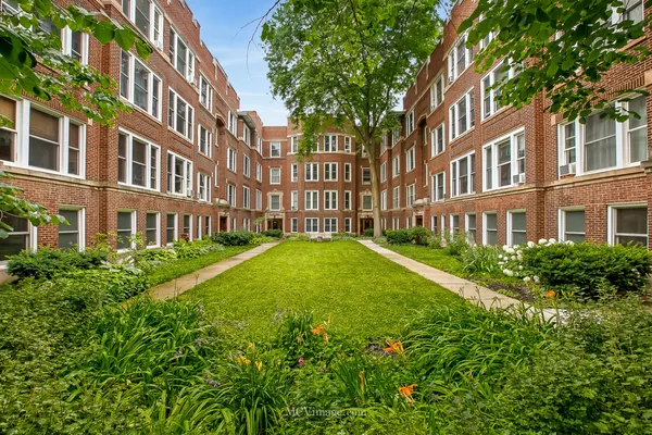 a view of a building next to a big yard and large trees