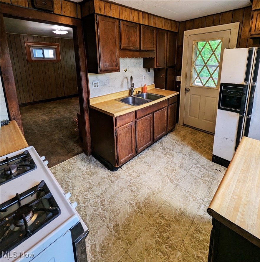 4745 Blythin Road Cleveland, OH 44125 - Photo 8 of 30 Kitchen with a sink, butcher block counters, white appliances, wood walls, and healthy amount of natural light
