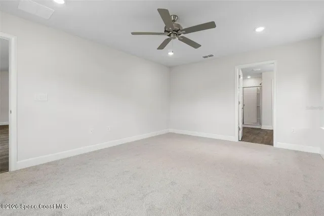 an empty room with a fan & a window