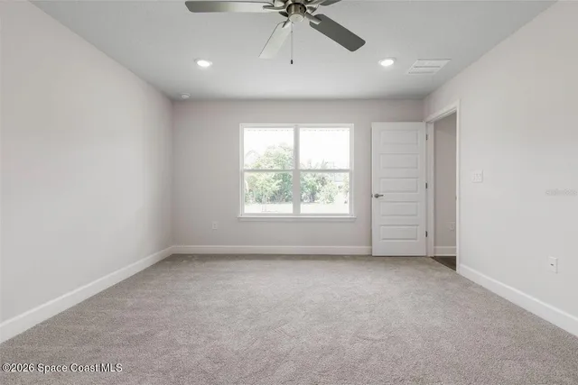 an empty room with windows and fan