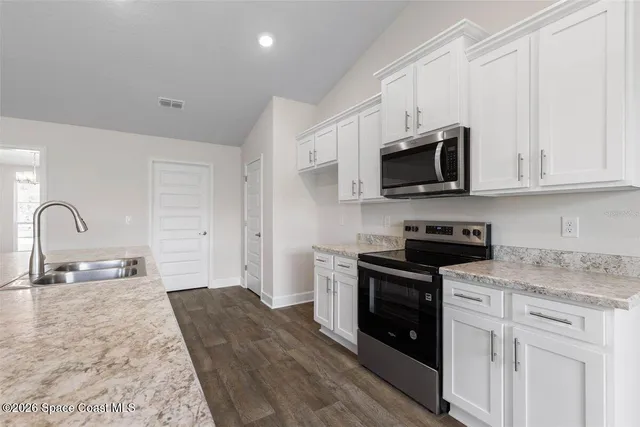 a kitchen with stainless steel appliances granite countertop a stove a sink and a microwave