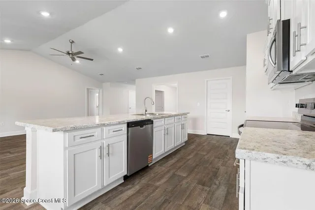 a kitchen with stainless steel appliances granite countertop a sink a stove a refrigerator and island with wooden floor